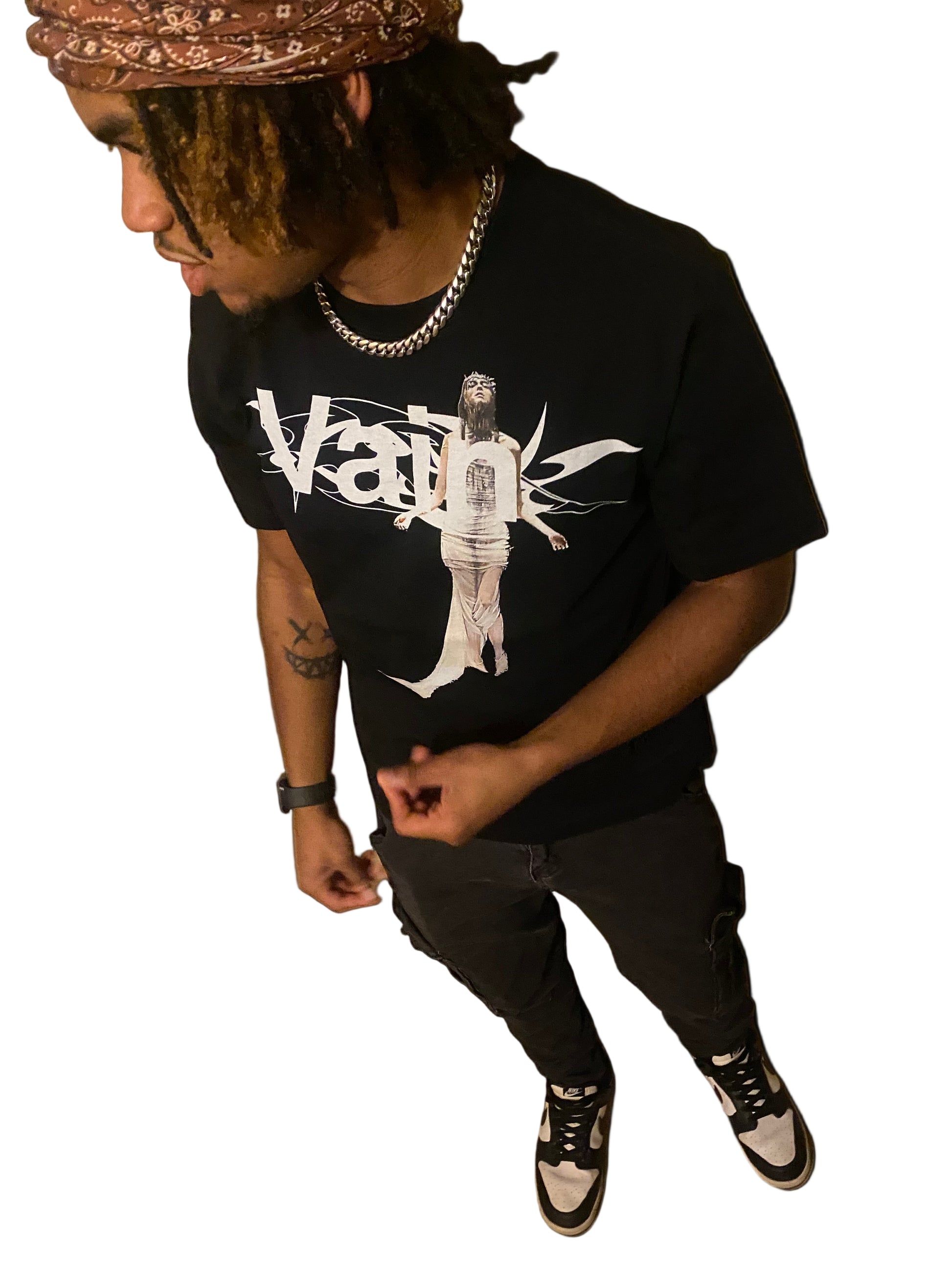 Person wearing a black t-shirt with white graphics and text, sitting on a white surface.